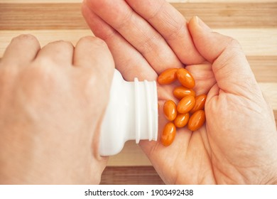 Woman Taking Coenzyme Q10 Pills Out Of A Bottle. Close Up.