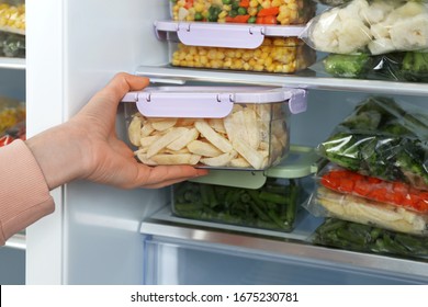 Woman Taking Container With Frozen Potato From Refrigerator, Closeup