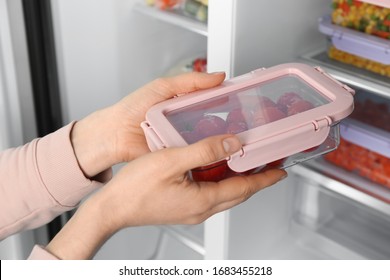 Woman Taking Container With Frozen Tomatoes From Refrigerator, Closeup