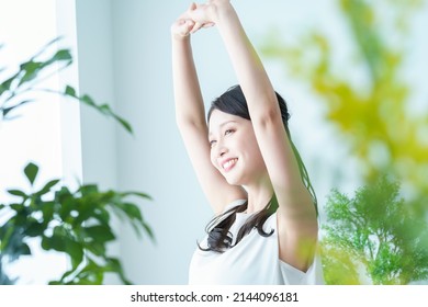 A woman taking a deep breath while bathing in the light by the window