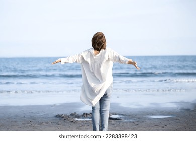 Woman taking deep breaths and stretching on sandy beach Stress free