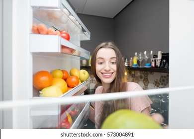 Woman taking food from the refrigerator. View from the inside - Shutterstock ID 573004891