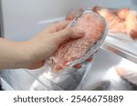 Woman taking frozen salmon steak out of fridge, closeup