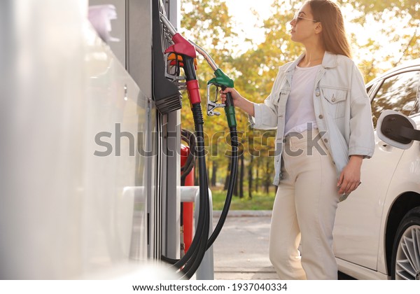 Woman\
taking fuel pump nozzle at self service gas\
station