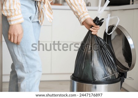 Woman taking garbage bag from trash bin in kitchen