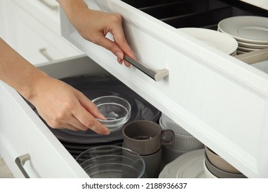 Woman Taking Glass Bowl From Open Drawer Of Kitchen Cabinet, Closeup