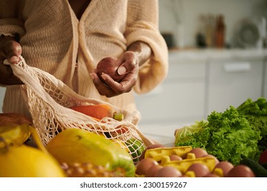 Woman taking groceries out of reusable bag after coming home from local market - Powered by Shutterstock