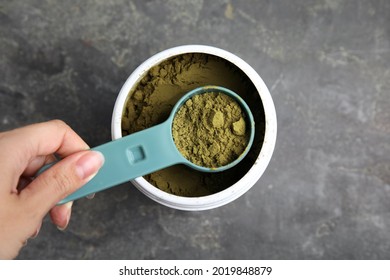 Woman Taking Hemp Protein Powder From Jar At Grey Table, Top View