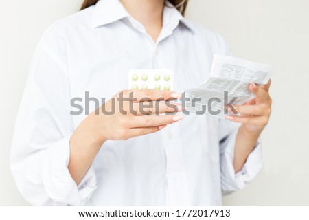 Woman Taking Medicine. Beautiful Young Female Holding Blister Pack With Pills In Hand And Reading Medical Instructions. Attractive Girl Looking At Instruction, Holding Pill Package. High Resolution