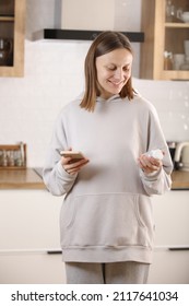 Woman Taking Medicine. Young Woman Holding Bottle With Pills In Hand And Reading Medical Instructions In The Cellphone. Ill Woman Looking At Medication Explanation Before Taking Prescription Drugs