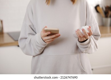 Woman Taking Medicine. Young Woman Holding Bottle With Pills In Hand And Reading Medical Instructions In The Cellphone. Ill Woman Looking At Medication Explanation Before Taking Prescription Drugs