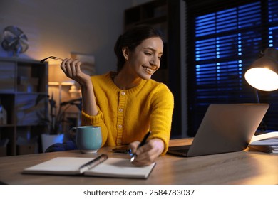 Woman taking notes while working at desk in home office
