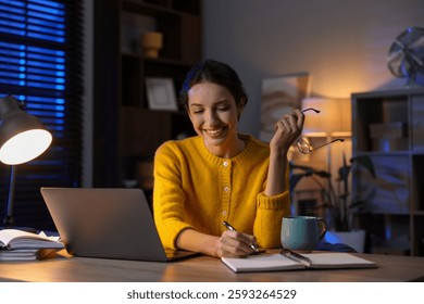 Woman taking notes while working at desk in home office