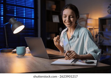 Woman taking notes while working at desk in home office