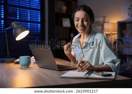 Woman taking notes while working at desk in home office