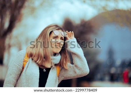 
Woman Taking off Her Glasses Trying to See in the Distance. Unhappy person feeling confused and unable to see with her eyeglasses
