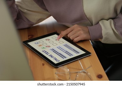 Woman Taking Online Test On Tablet At Desk, Closeup