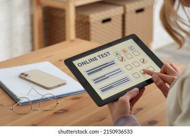 Woman Taking Online Test On Tablet At Desk Indoors, Closeup