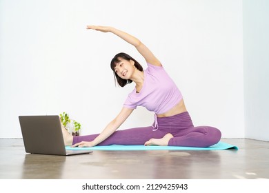 A Woman Taking An Online Yoga Lesson Using A Laptop