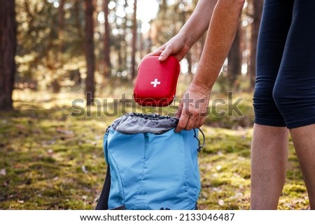Woman taking out first aid kit from backpack. Travel insurance for all eventualities. Prepared for health problems during hiking