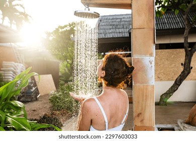 Woman taking an outdoor shower at a dream vacation resort. - Powered by Shutterstock