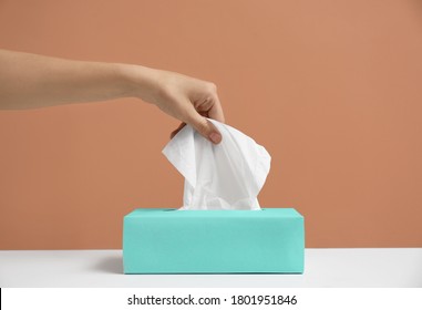 Woman taking paper tissue from box on light brown background, closeup - Shutterstock ID 1801951846