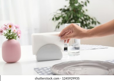 Woman taking paper tissue from ceramic napkin holder on served table