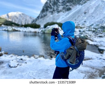 Woman Taking Photo Of The Blue Clear Mountain Lake With Snowy Hill Mountain Peaks, Western Tatras Mountains, Rohace Slovakia, Autumn