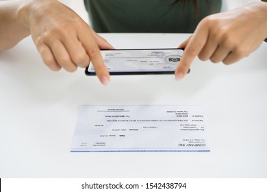 Woman Taking Photo Of Cheque To Make Remote Deposit In Bank