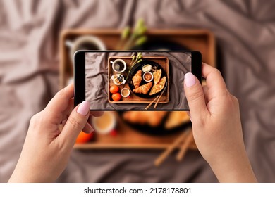Woman taking photo of continental breakfast on wooden tray with smartphone. Food blogger using phone to capture meal. Lifestyle trend - posting and sharing food pictures on social media. - Shutterstock ID 2178178801