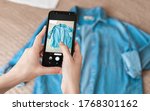 Woman taking photo of denim shirt on smartphone 
