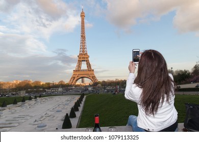 Woman taking photo of Eiffel Tower in Paris, France with cellpho
