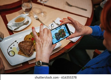 A Woman Taking A Photo Of Food On A Plate