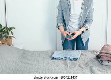 Woman Taking Photo Of Jeans On Smartphone. Concept Of Secondhand, Online Sale, Sustainability.