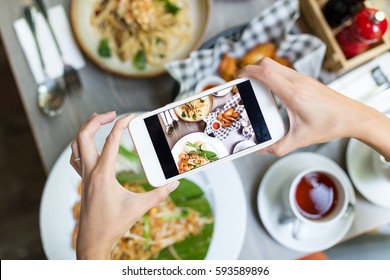 Woman taking photo on cellphone on dish - Powered by Shutterstock