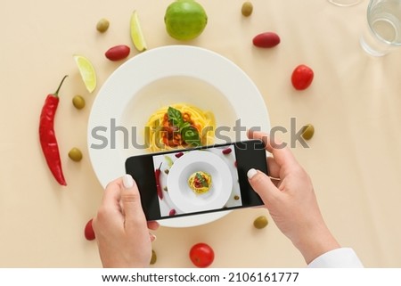 Woman taking photo of tasty Pasta Puttanesca in restaurant Foto d'archivio © 