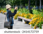 Woman taking photos of beautiful flowers using smartphone. Anchorage. Alaska. 