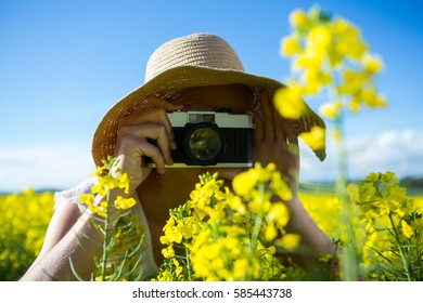 Woman taking picture from camera in mustard field on a sunny day - Powered by Shutterstock