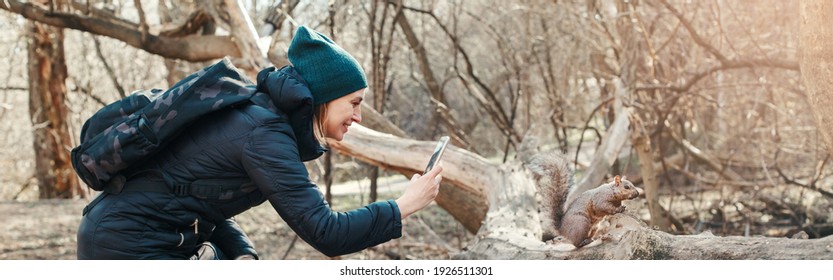 Woman Taking Picture Photo Of Squirrel In Park. Tourist Traveler Girl Snapping Smartphone Photos Of Wild Animal In Forest. Fun Outdoor Activity And Blogging Vlogging Online. Web Banner Header.