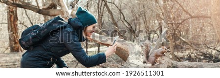 Woman taking picture photo of squirrel in park. Tourist traveler girl snapping smartphone photos of wild animal in forest. Fun outdoor activity and blogging vlogging online. Web banner header.