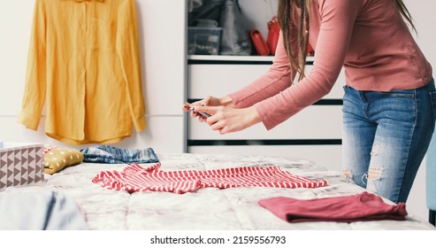 Woman taking pictures of her clothes on the bed, she wants to sell her second hand clothes online