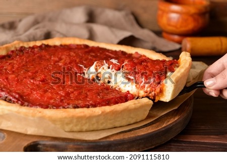 Woman taking piece of tasty Chicago-style pizza on wooden background, closeup Stock photo © 