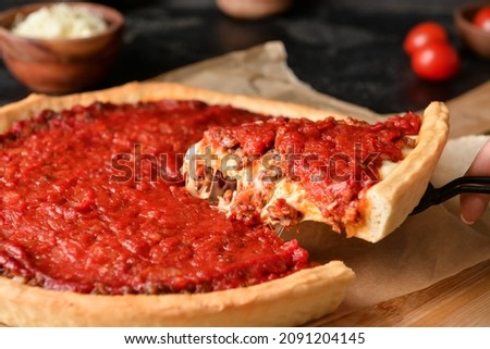 Woman taking piece of tasty Chicago-style pizza on dark background, closeup Stock photo © 