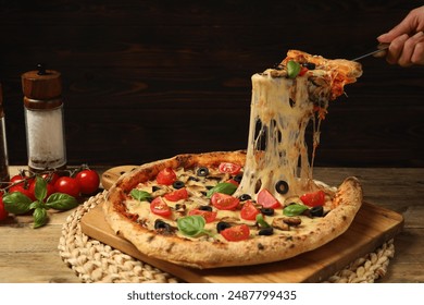 Woman taking piece of tasty pizza with melted cheese at wooden table, closeup - Powered by Shutterstock