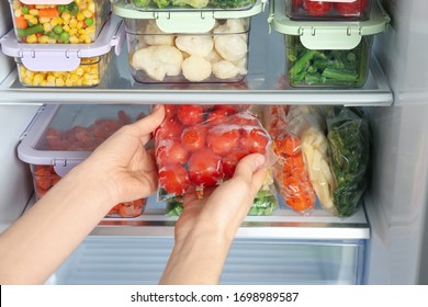 Woman taking plastic bag with frozen tomatoes from refrigerator, closeup