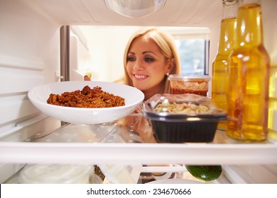 Woman Taking Plate Of Leftover Food From The Fridge