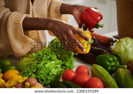Woman taking red and yellow bell peppers for recipe