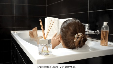 A woman taking a relaxing bath while reading a book. Importance of personal enrichment and mental wellness - Powered by Shutterstock