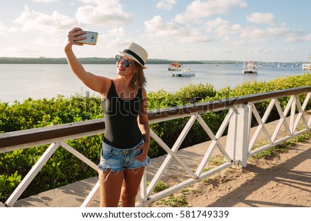Woman taking self portrait in tourist spot "Jacare river beach", near Joao Pessoa, Brazil