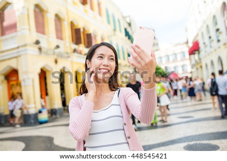 Woman taking selfie by mobile phone in Macao city